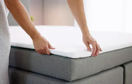 surmatelas sur un lit gris dans une chambre claire